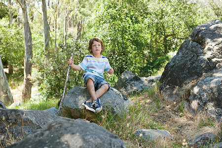 男孩坐在岩石上图片