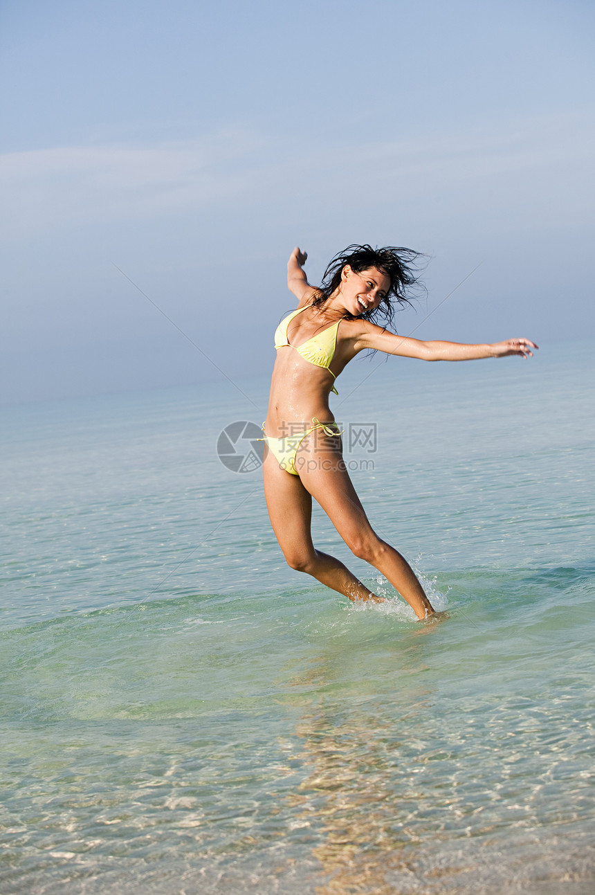 年轻妇女在海上跳跃图片