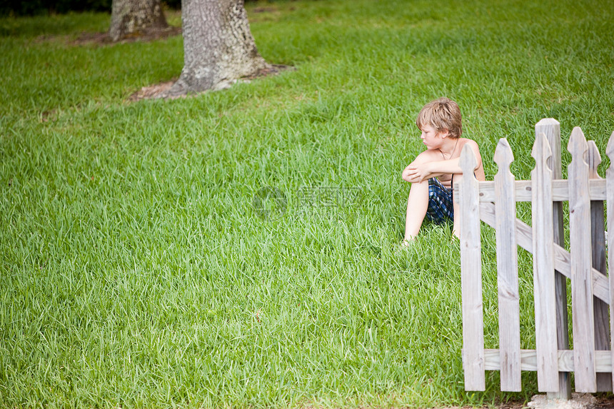 男孩坐在绿草上图片