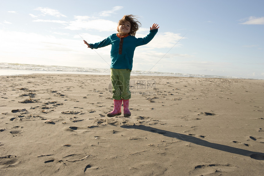 年轻女孩在沙滩上跳跃图片