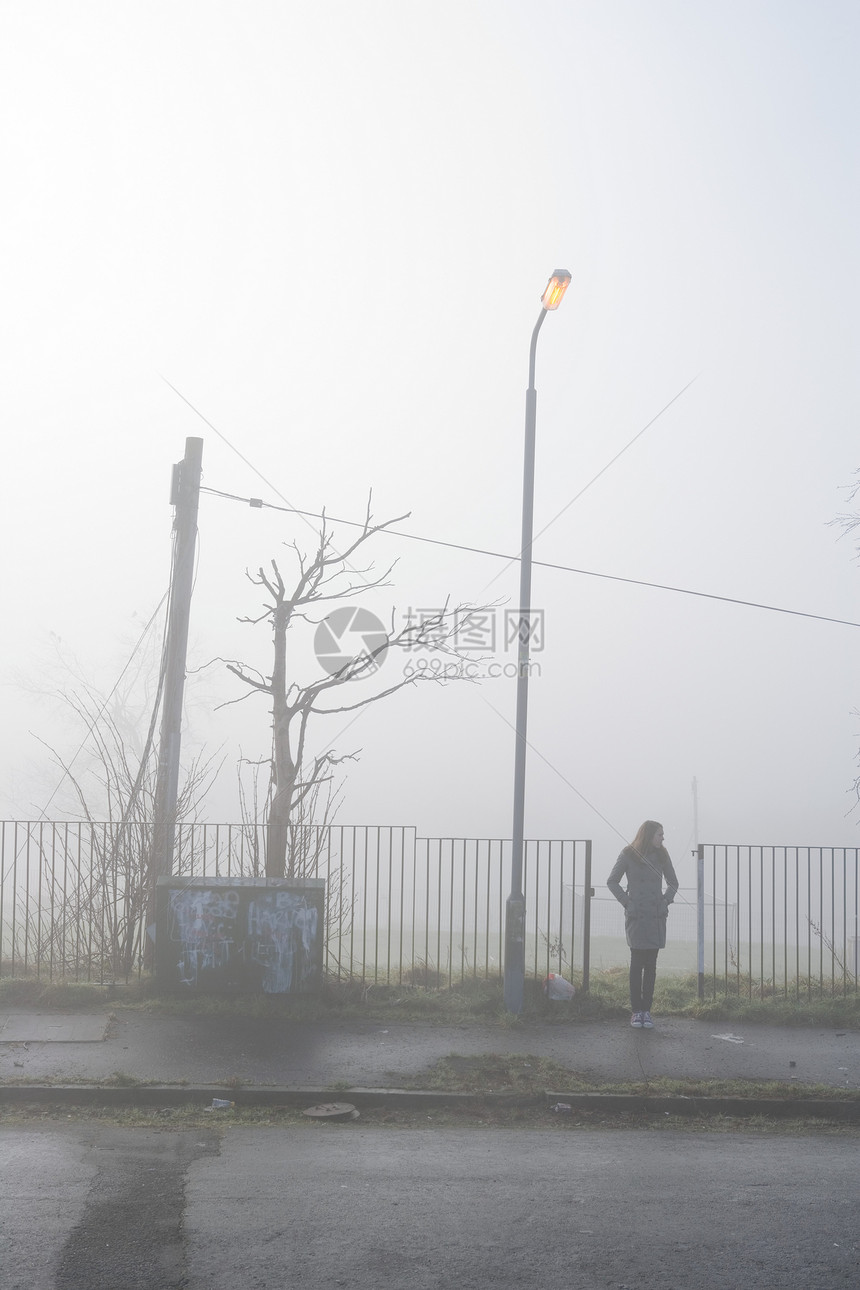 少女站在烟雾中的人行道上图片