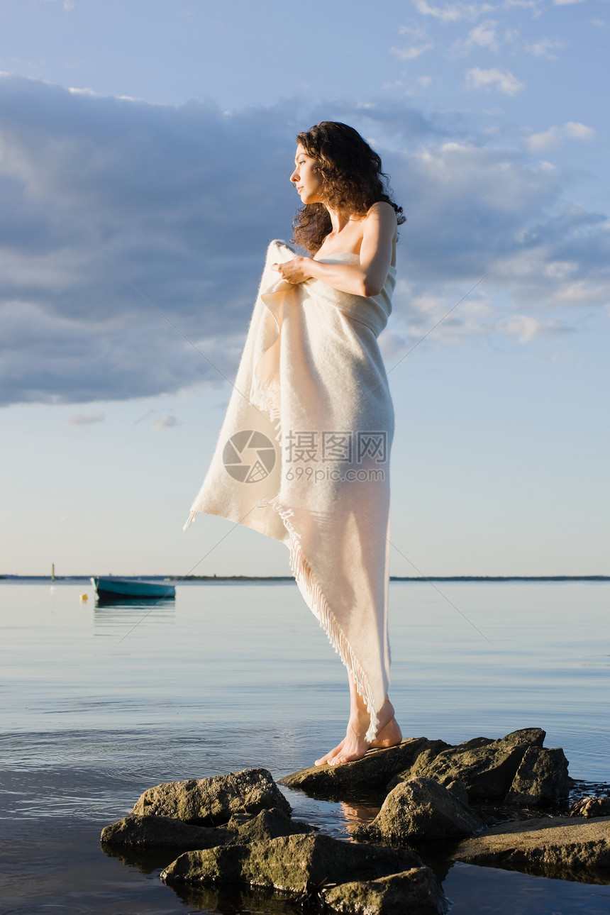 披着毯子的妇女站在海边图片