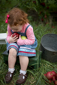 坐在长椅上拿着苹果的女孩图片