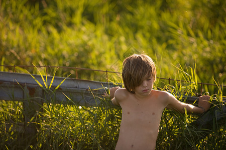 在野外靠着栅栏的男孩图片