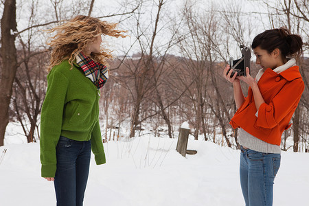 少女在雪中用相机拍朋友图片