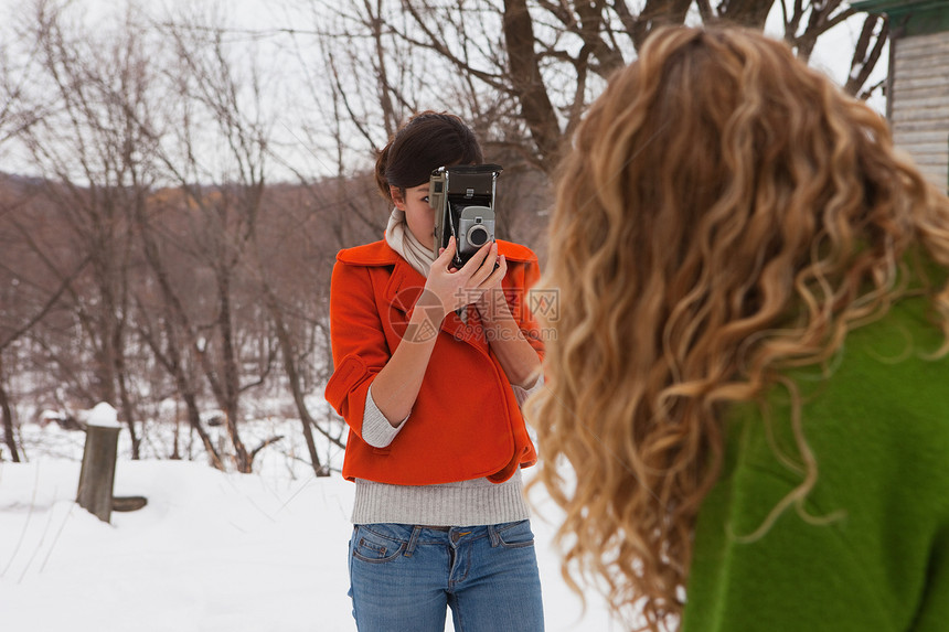 少女在雪中用相机拍朋友图片