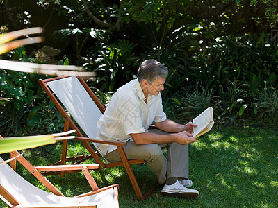 坐在花园看书的男子图片