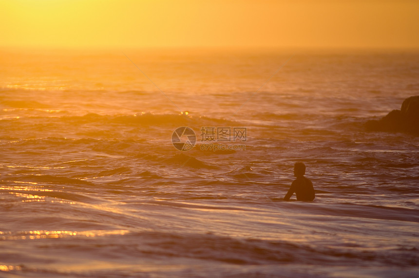 日落时海中冲浪的男子图片
