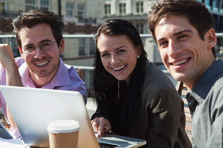 三个人在使用笔记本电脑时对镜头微笑图片