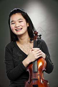 年轻亚洲少女拿着小提琴微笑的肖像高清图片