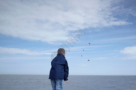 一宅定江山小男孩把石头扔进大海背景