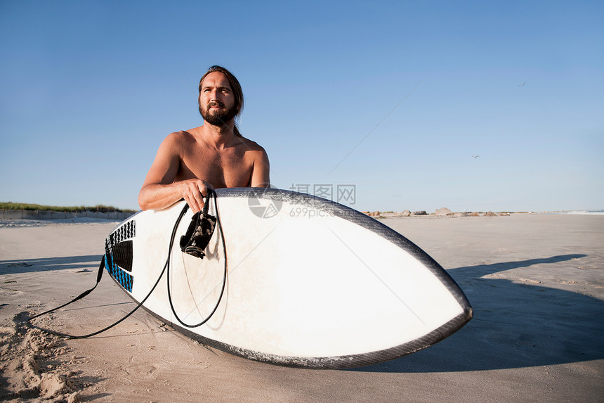 海滩上手拿冲浪板的商人图片