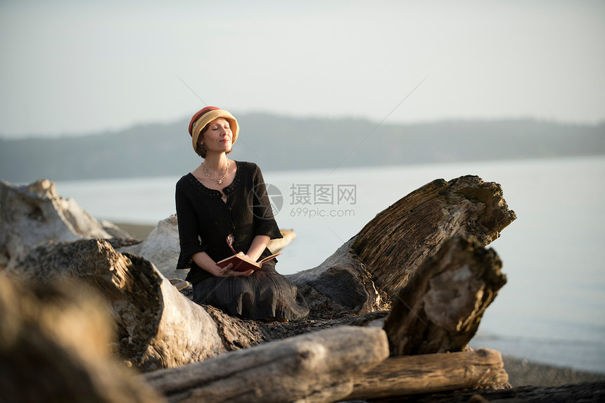 坐在漂浮木上的女人图片