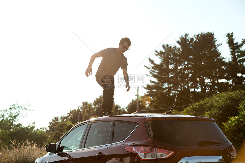 青年男子在车顶上行走图片