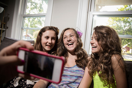 一群女孩用智能手机拍照片图片
