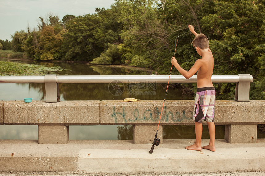 男孩在桥上拿着鱼竿钓鱼图片