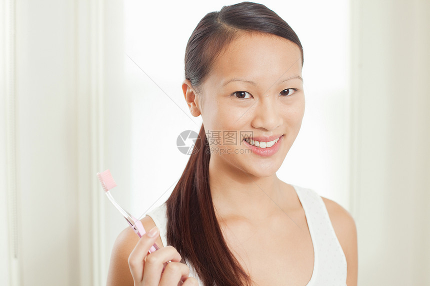 洗手间中拿着牙刷的年轻女性图片