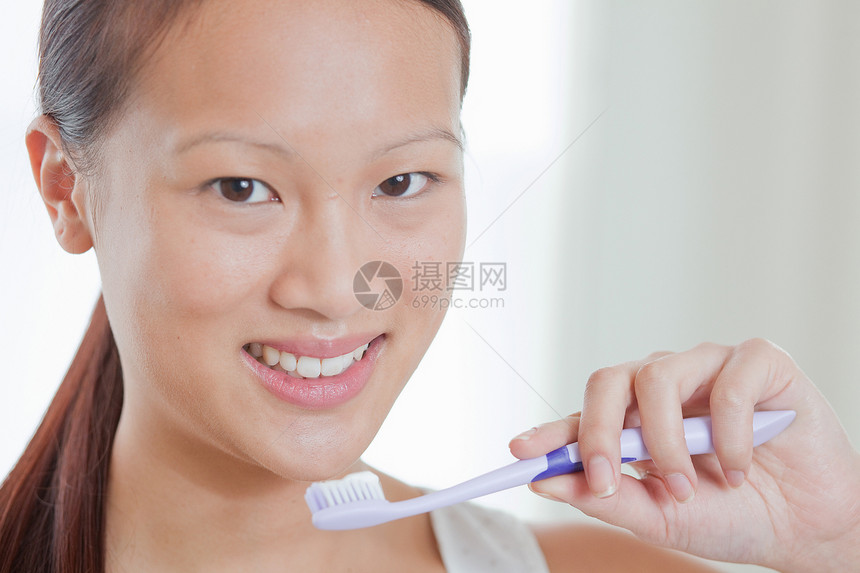 洗手间中拿着牙刷的年轻女性图片