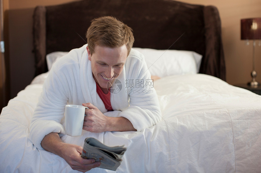 男人在床上阅读报纸图片