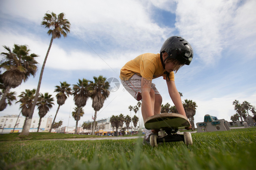 男孩把滑板放在公园的草地上图片