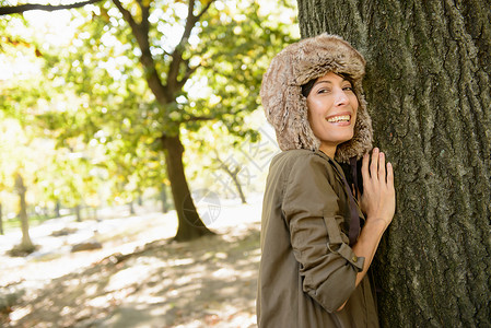 在公园抱树微笑的女人图片