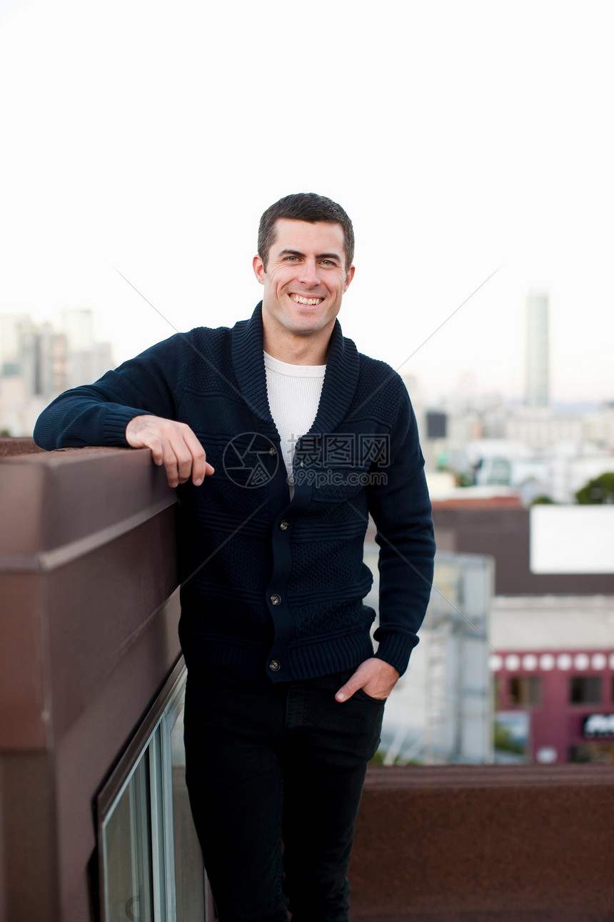 微笑的男人站在城市阳台上图片