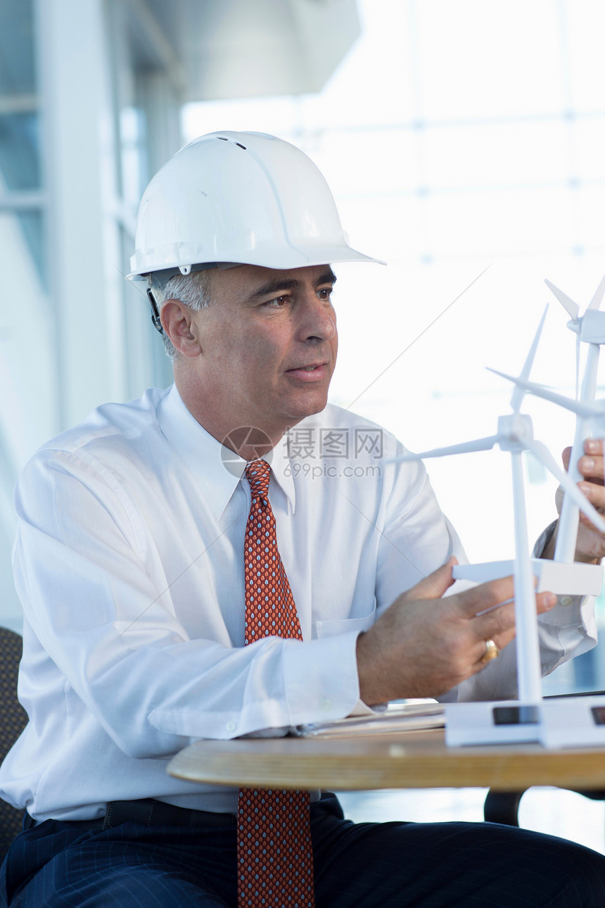 坐在风力涡轮机模型边的工程师图片