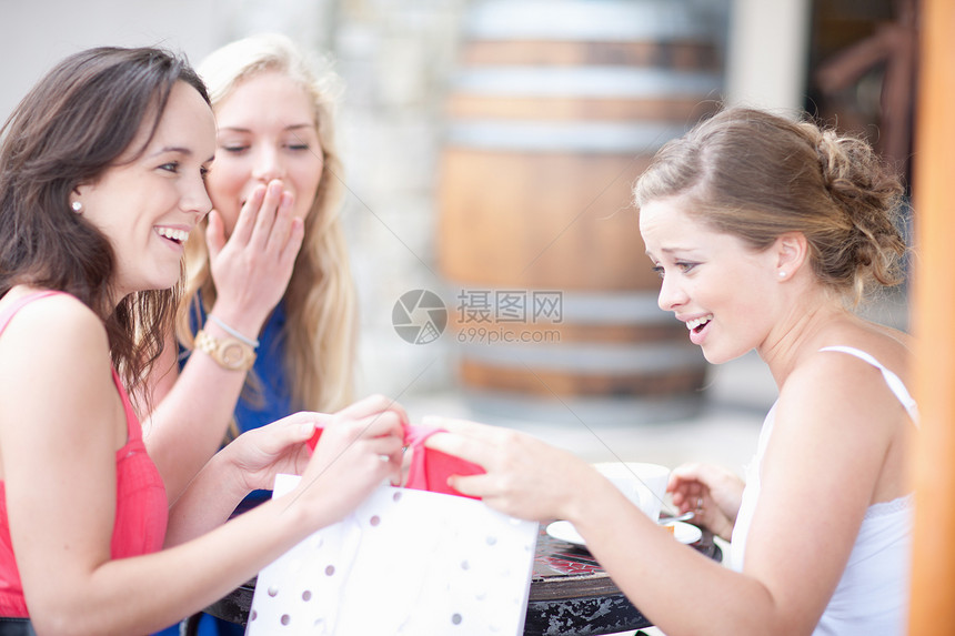 年轻妇女互相展示她们的购物带图片