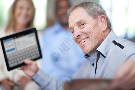 拿着平板电脑微笑的老年男子图片