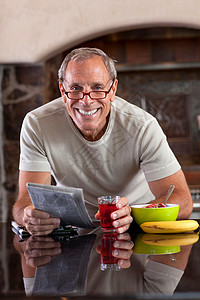 老年男子在早餐时看报纸图片