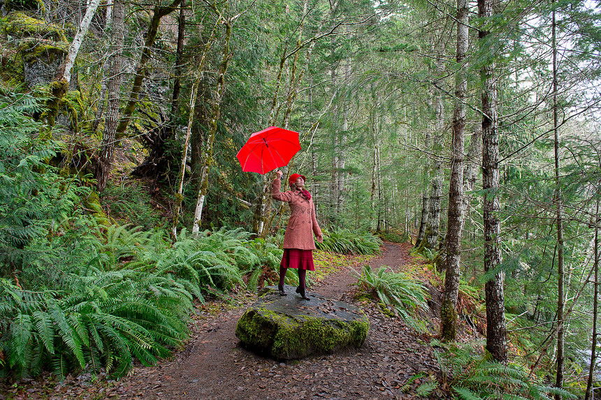 带着雨伞在森林中行走的女性图片