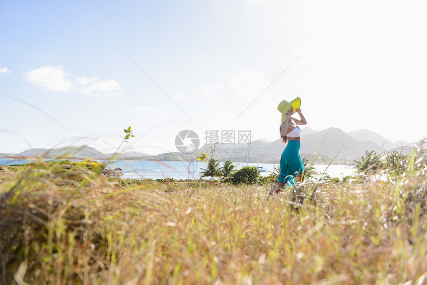 戴着遮阳帽的美女站在田野中图片