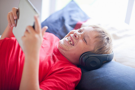 男孩在床上听音乐和玩电脑图片