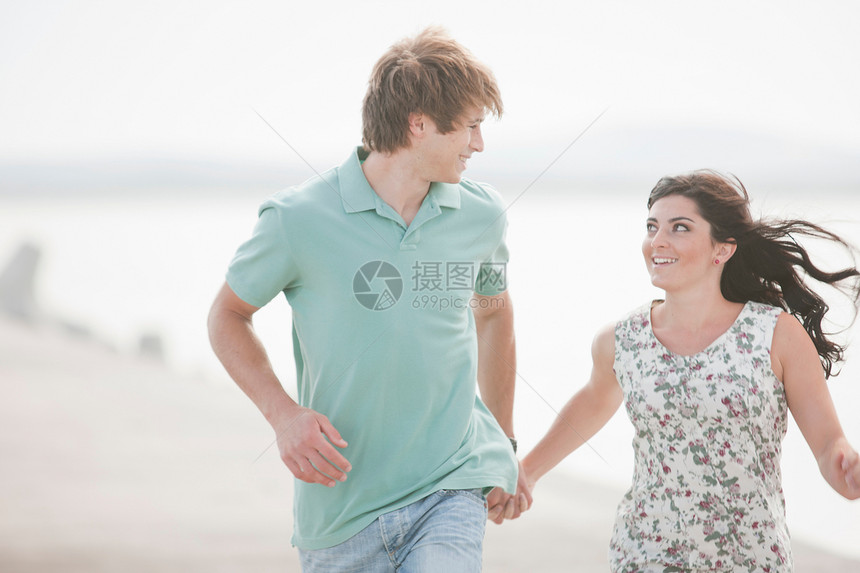 年轻情侣一起在海边奔跑        图片