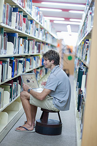男学生在图书馆使用笔记本电脑图片