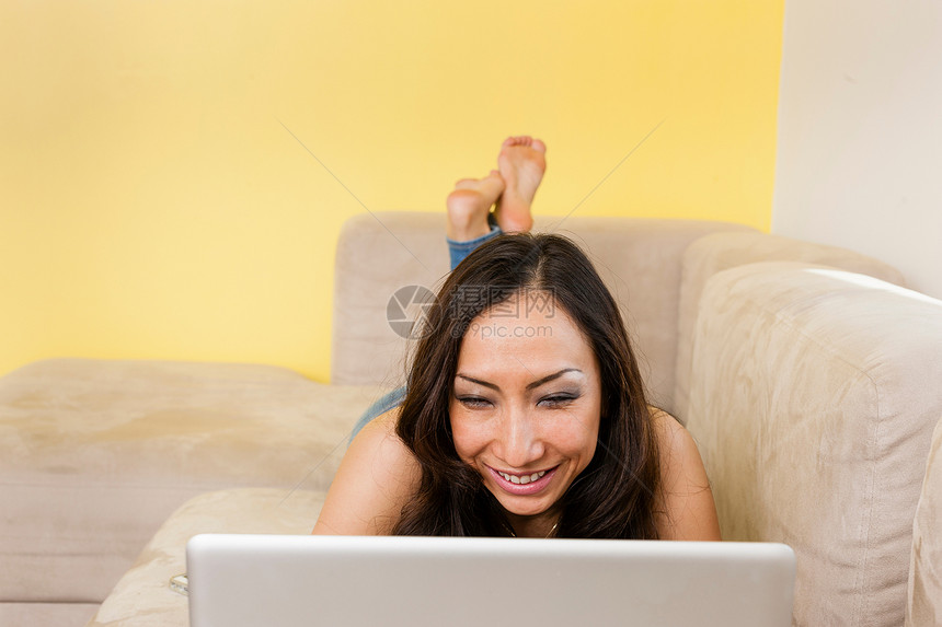 在沙发上躺着的成年女子看笔记本电脑图片