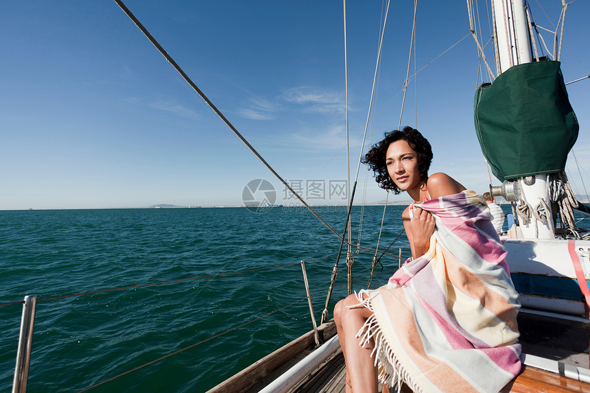 在游艇上用毛毯包着的年轻女子图片