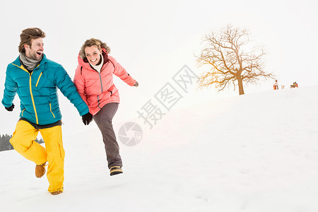 中年夫妇在雪地中牵手奔跑图片