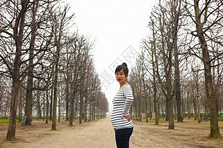 女性站在树木中的大道上图片