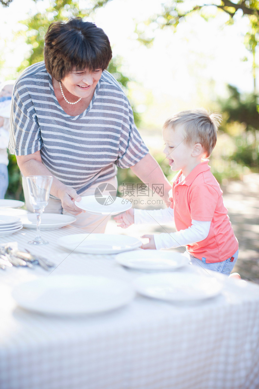 男孩和祖母在户外摆餐桌准备吃饭图片