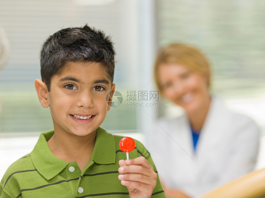 在牙医办公室拿着棒棒糖的年轻男孩肖像图片
