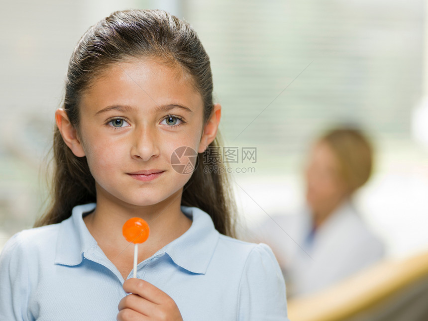 在牙医办公室拿着棒棒糖的年轻女孩图片