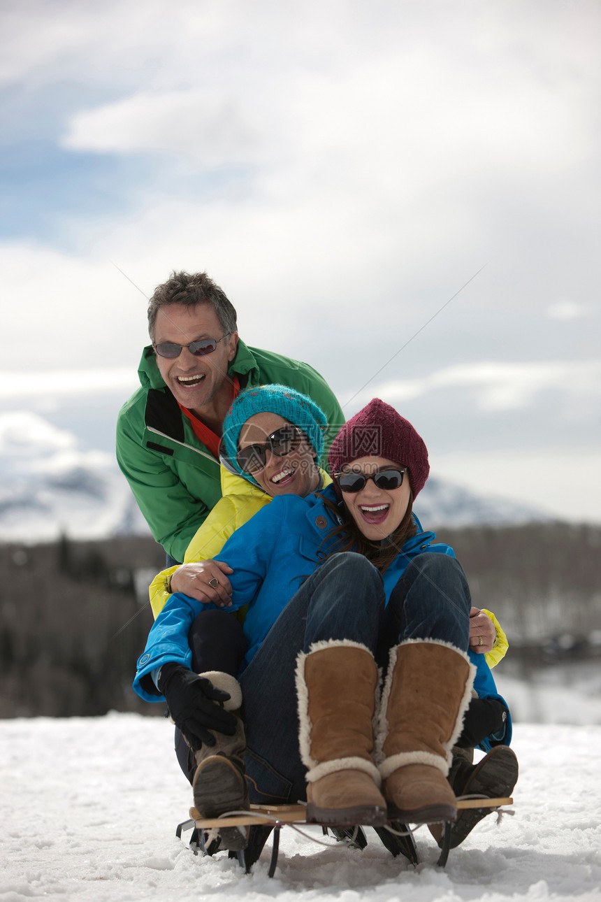 三个朋友坐在雪地的橇上图片