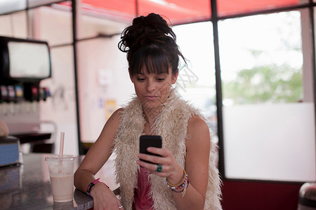 在餐厅看手机的年轻妇女图片
