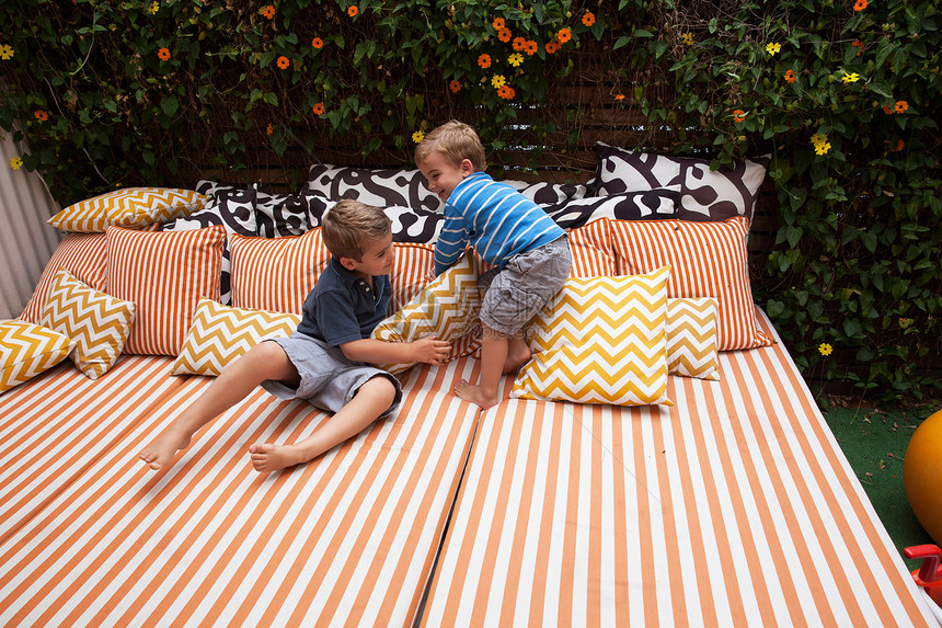两个男孩玩室外家具和坐垫图片