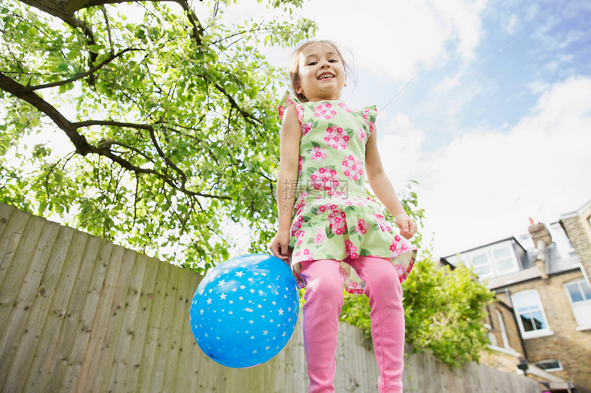 年轻女孩拿着气球跳进花园图片