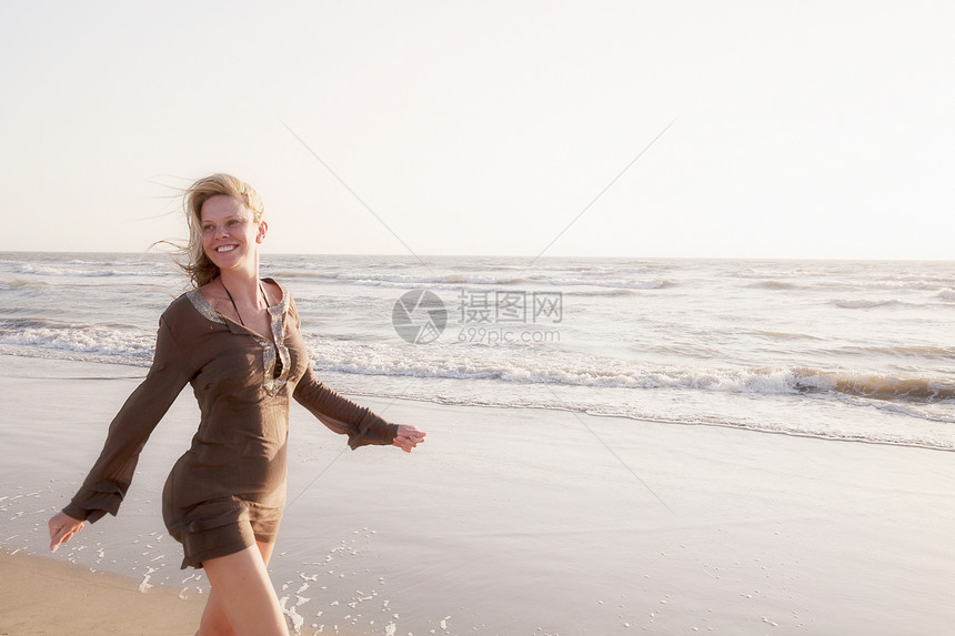 成年女子在海滩上微笑着走着图片