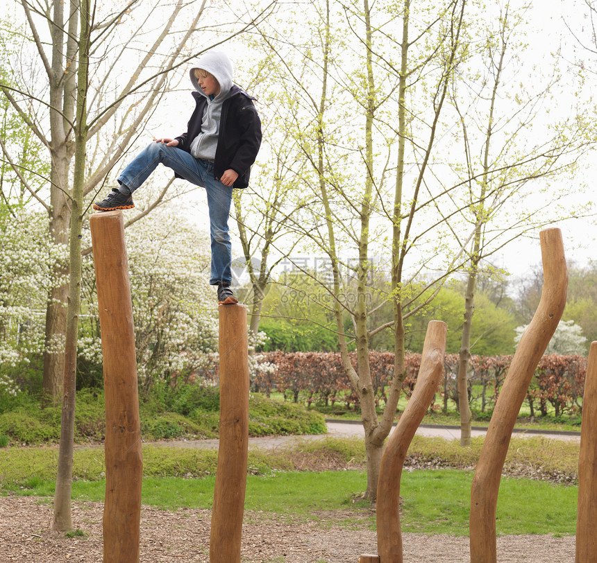 男孩踩在公园木桩上图片