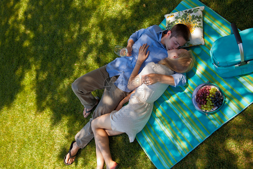 年轻夫妇在野餐毯子上亲吻图片