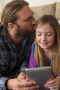 女孩与父亲一起看平板电脑图片
